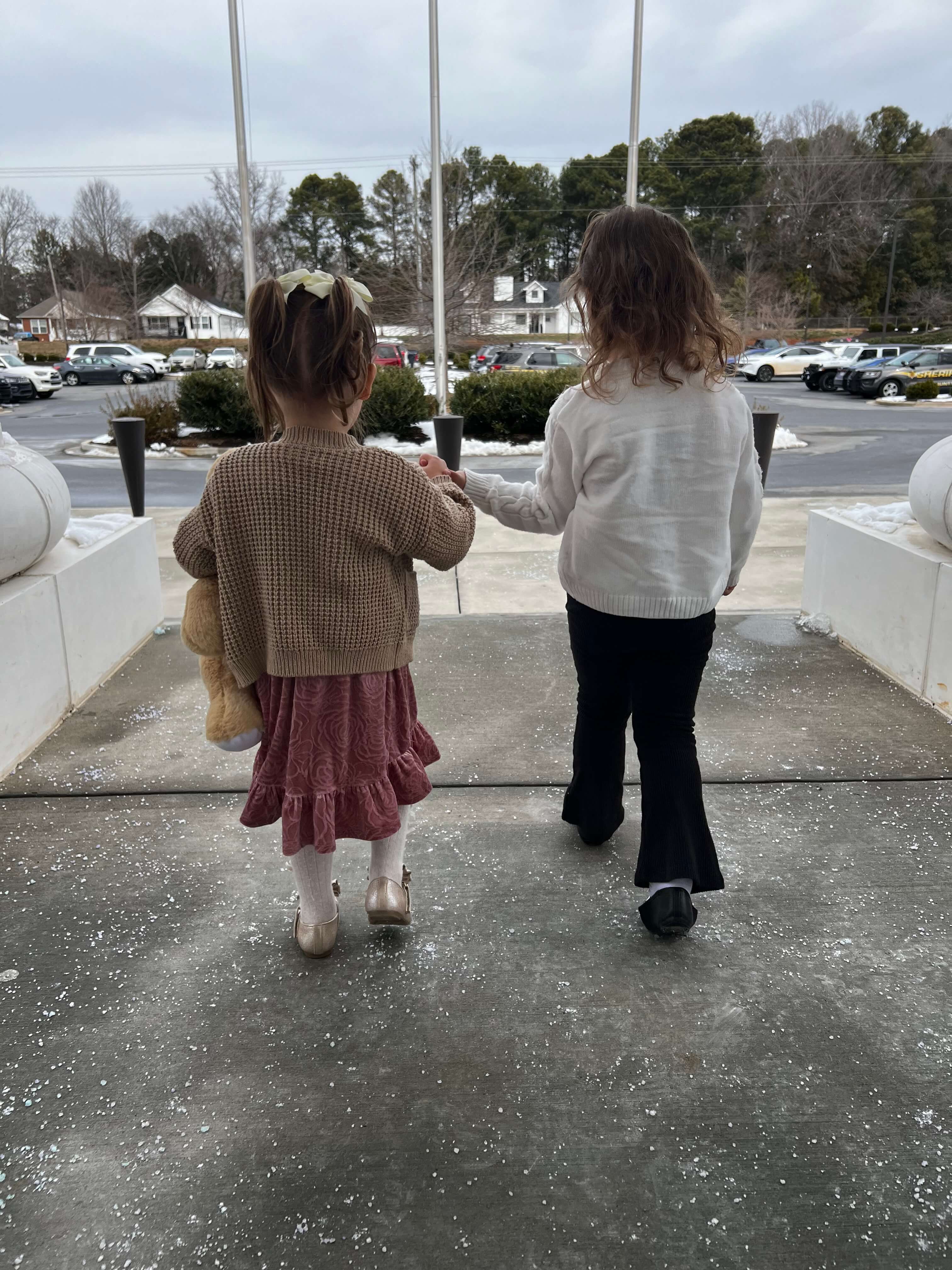 Two little girls walking out of a courthouse hand in hand
